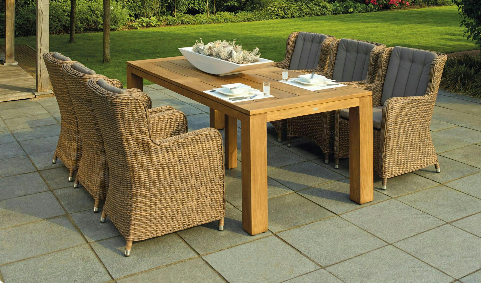 Wicker chairs around a wooden table on a back patio.