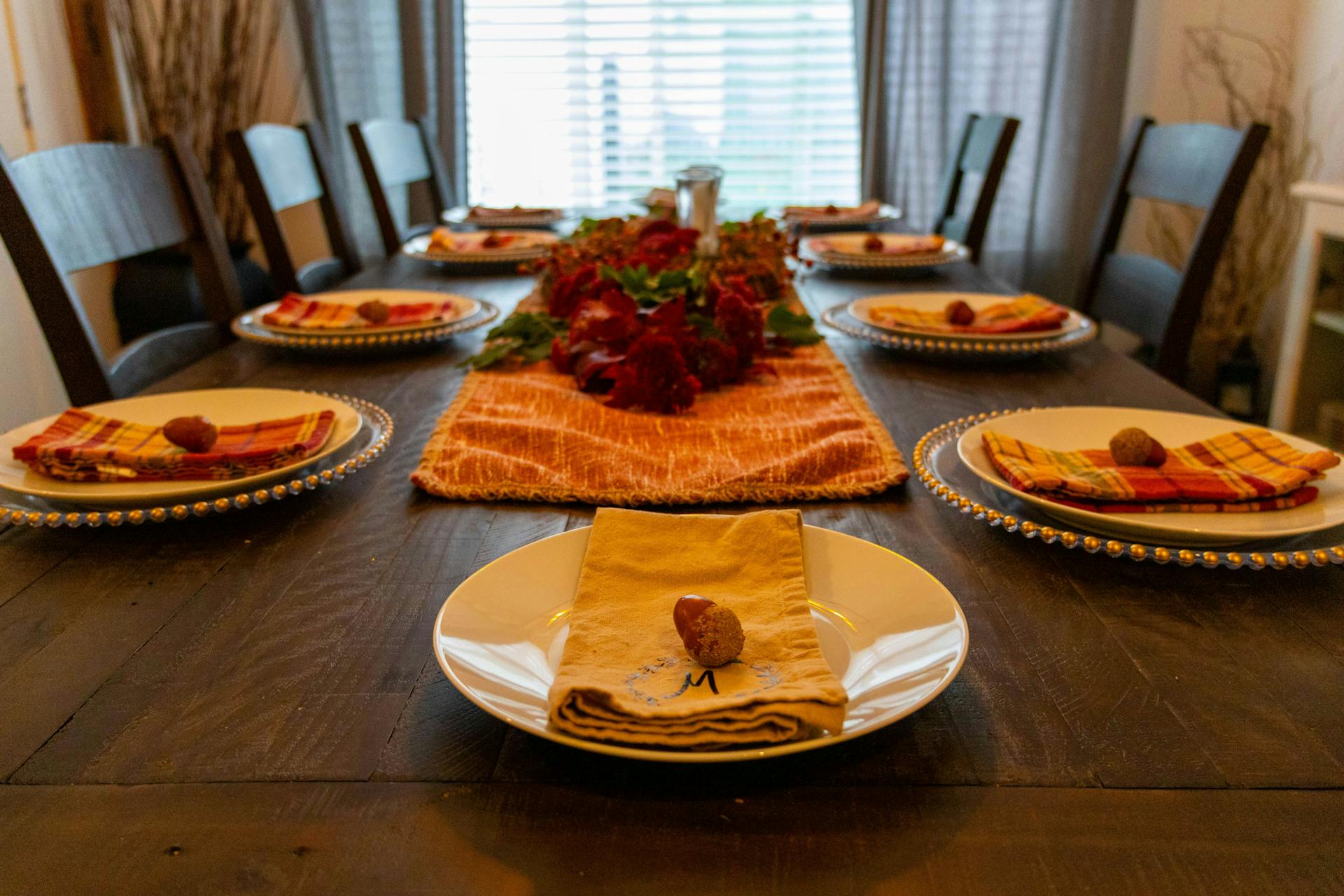 A Thanksgiving table set with a decorative centerpiece, plates, and napkins