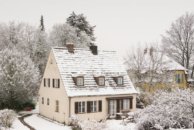 A snow-covered house in a suburban neighborhood