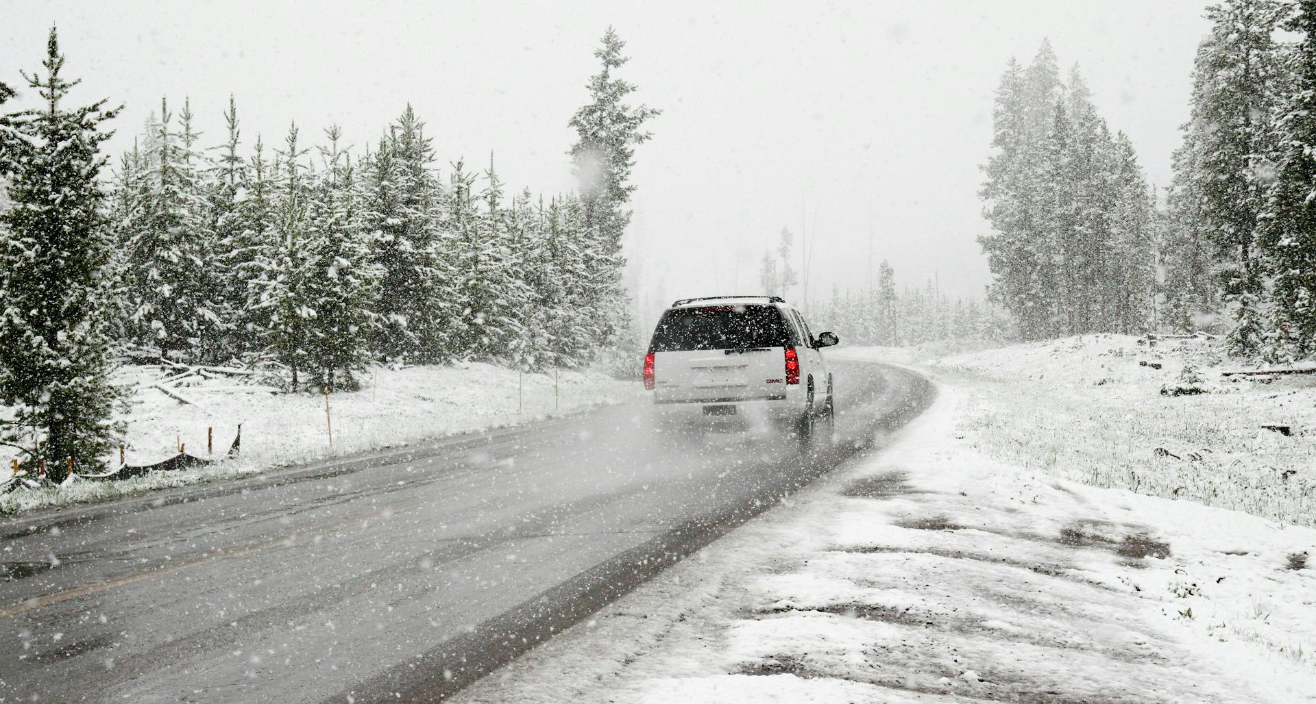 A white SUV driving on a snowy road