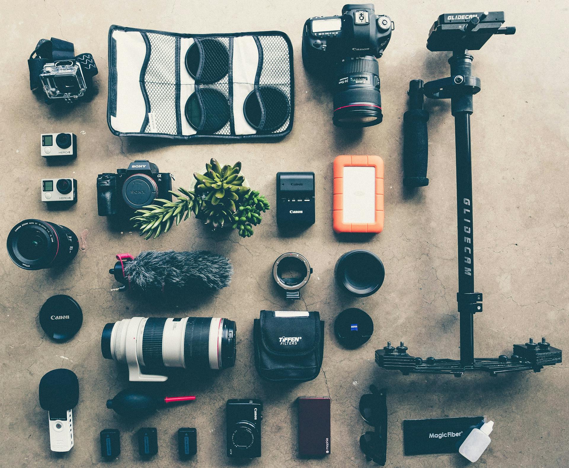A variety of photography equipment, including lenses, camera bodies, batteries, and more, set out on the floor.