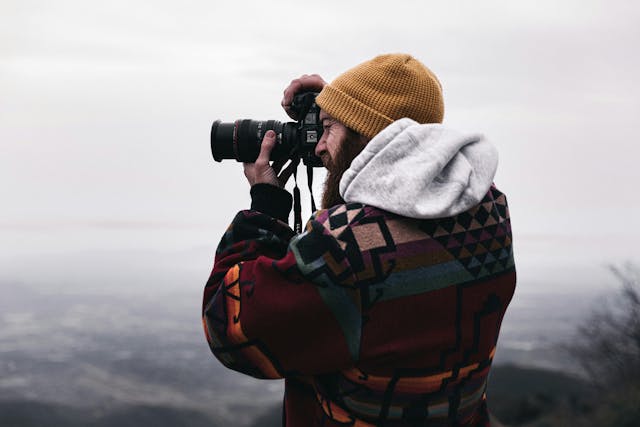 A photographer taking aim at a shot on top of a mountain or tall hill