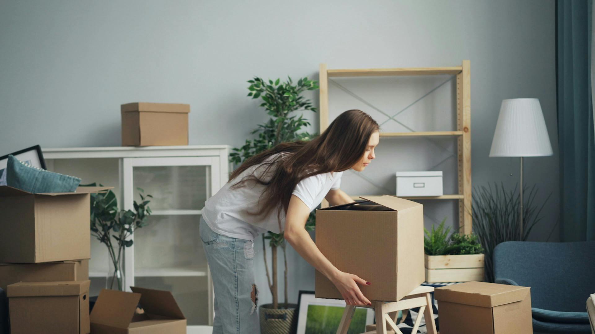 A woman setting a box down in her new apartment.