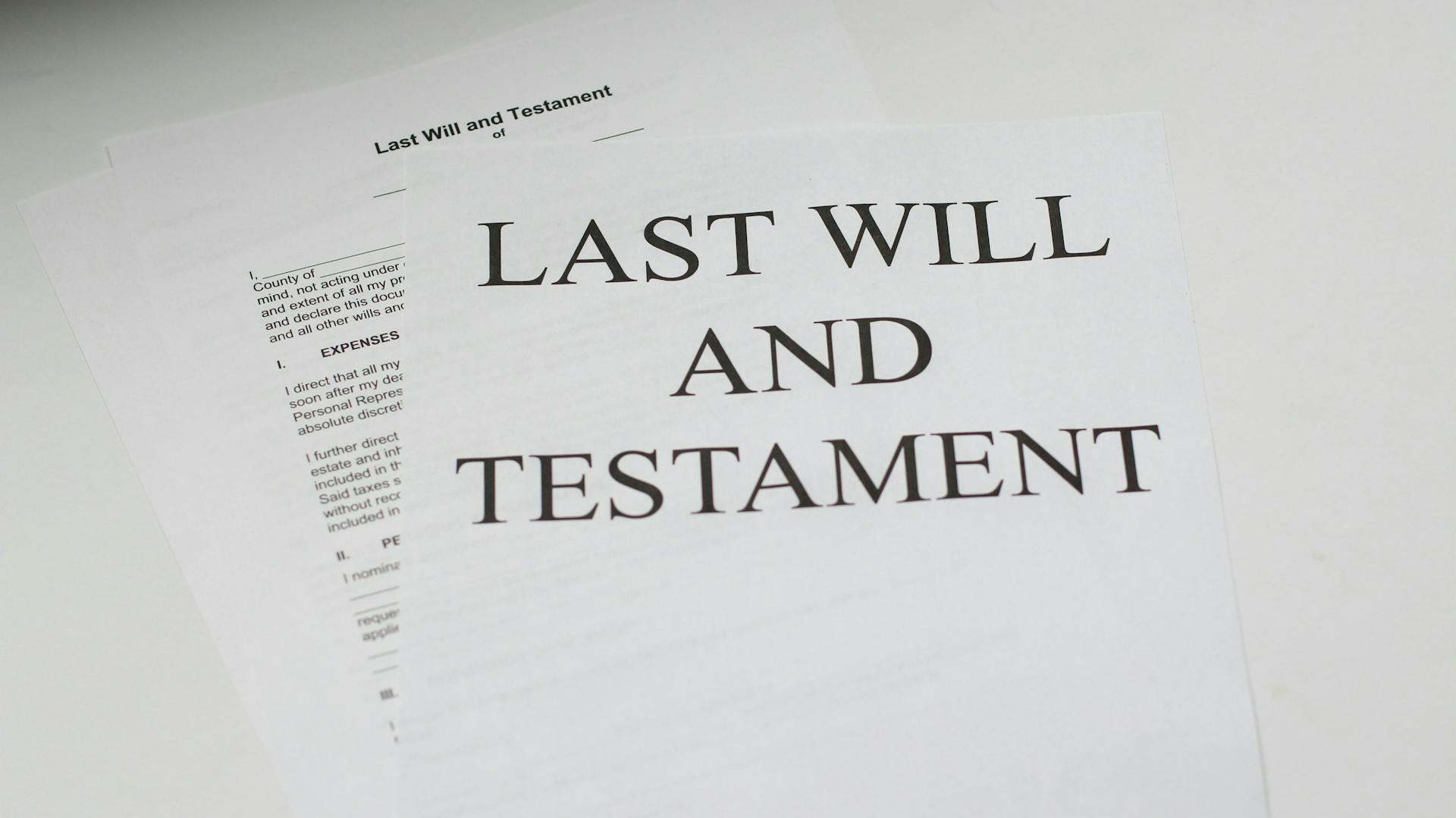 A stack of papers labeled, “Last Will and Testament” on a white desk.