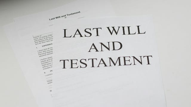 A stack of papers labeled, “Last Will and Testament” on a white desk.