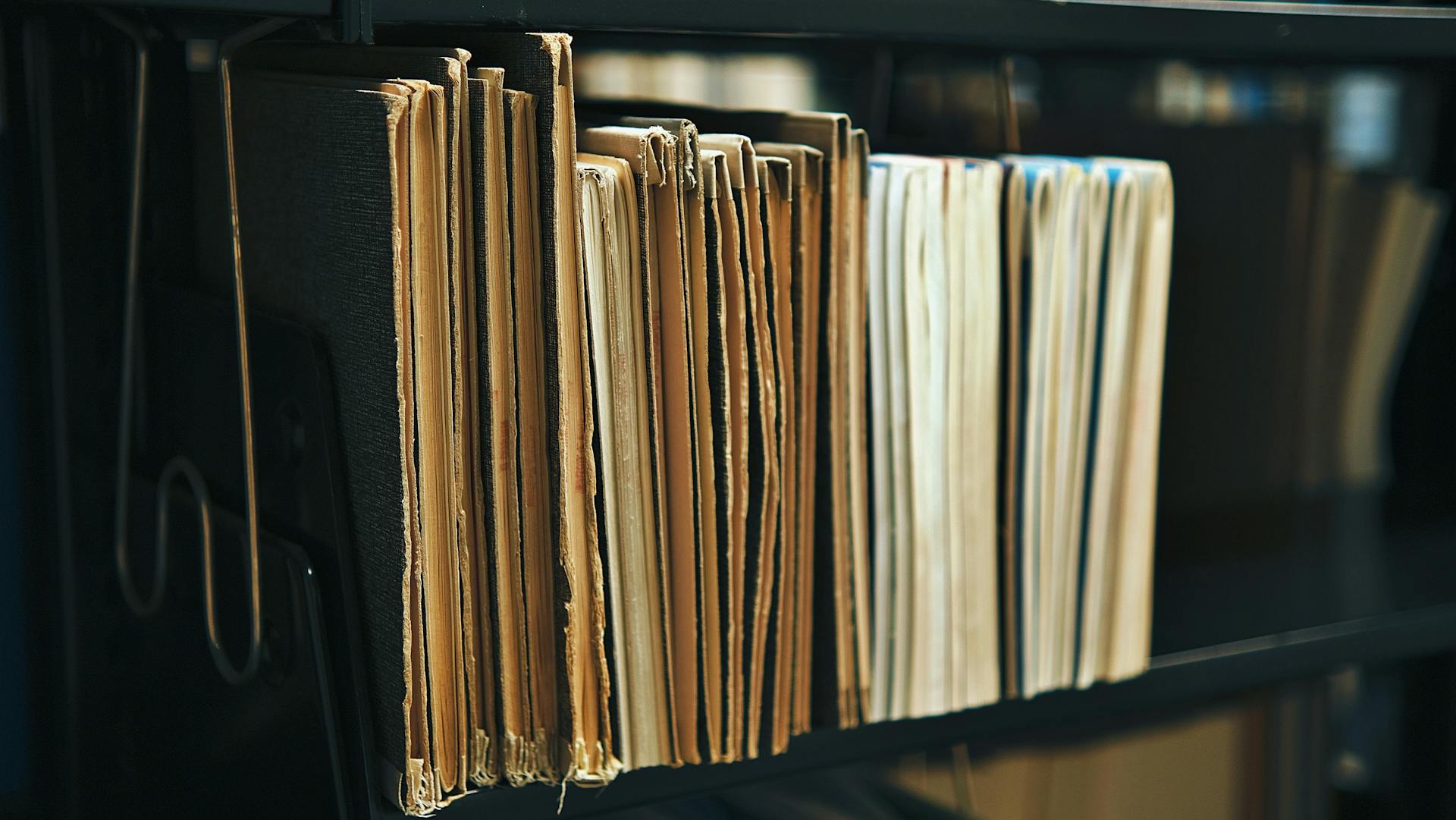 A stack of file folders stacked on a shelf.
