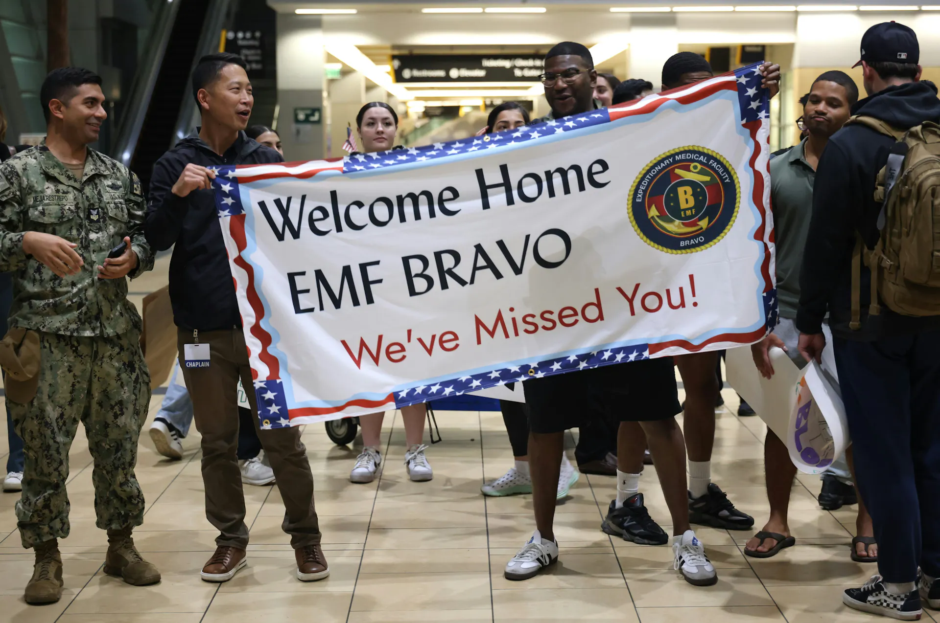 People holding a welcome home banner at the airport for a returning military member.