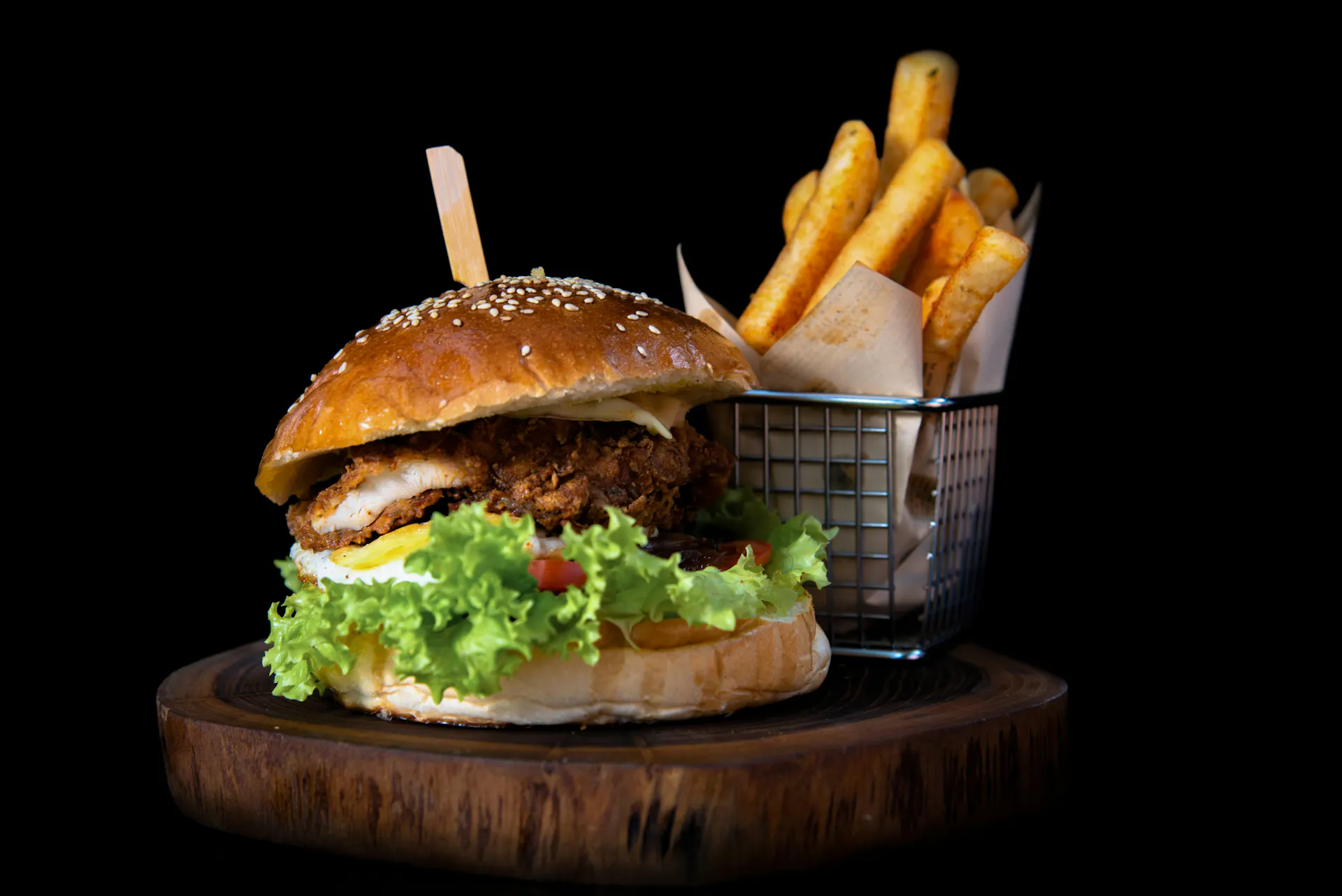 A hamburger and fries served on a wooden tray.