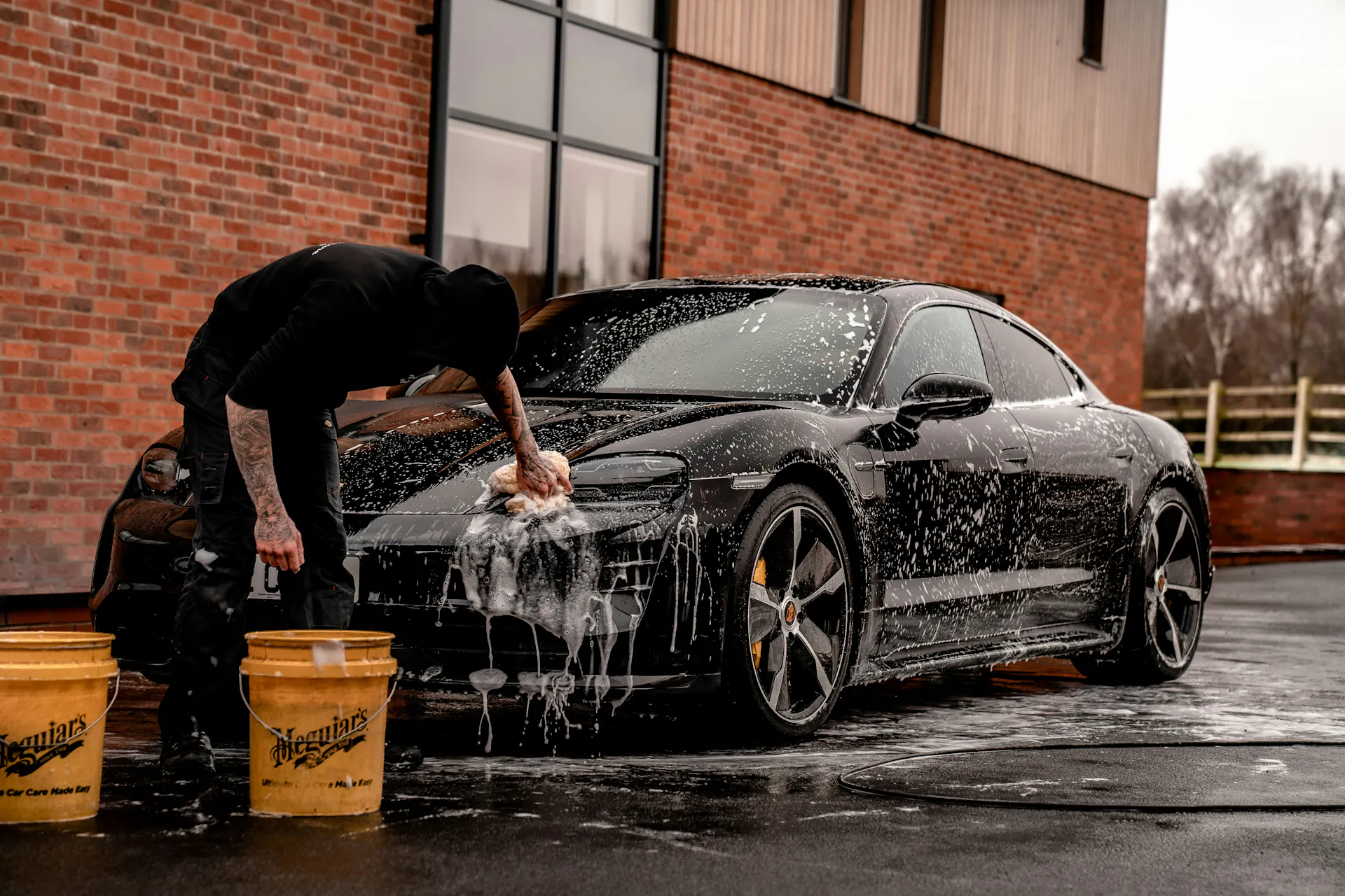 A close-up of someone washing and detailing the front of a vehicle.