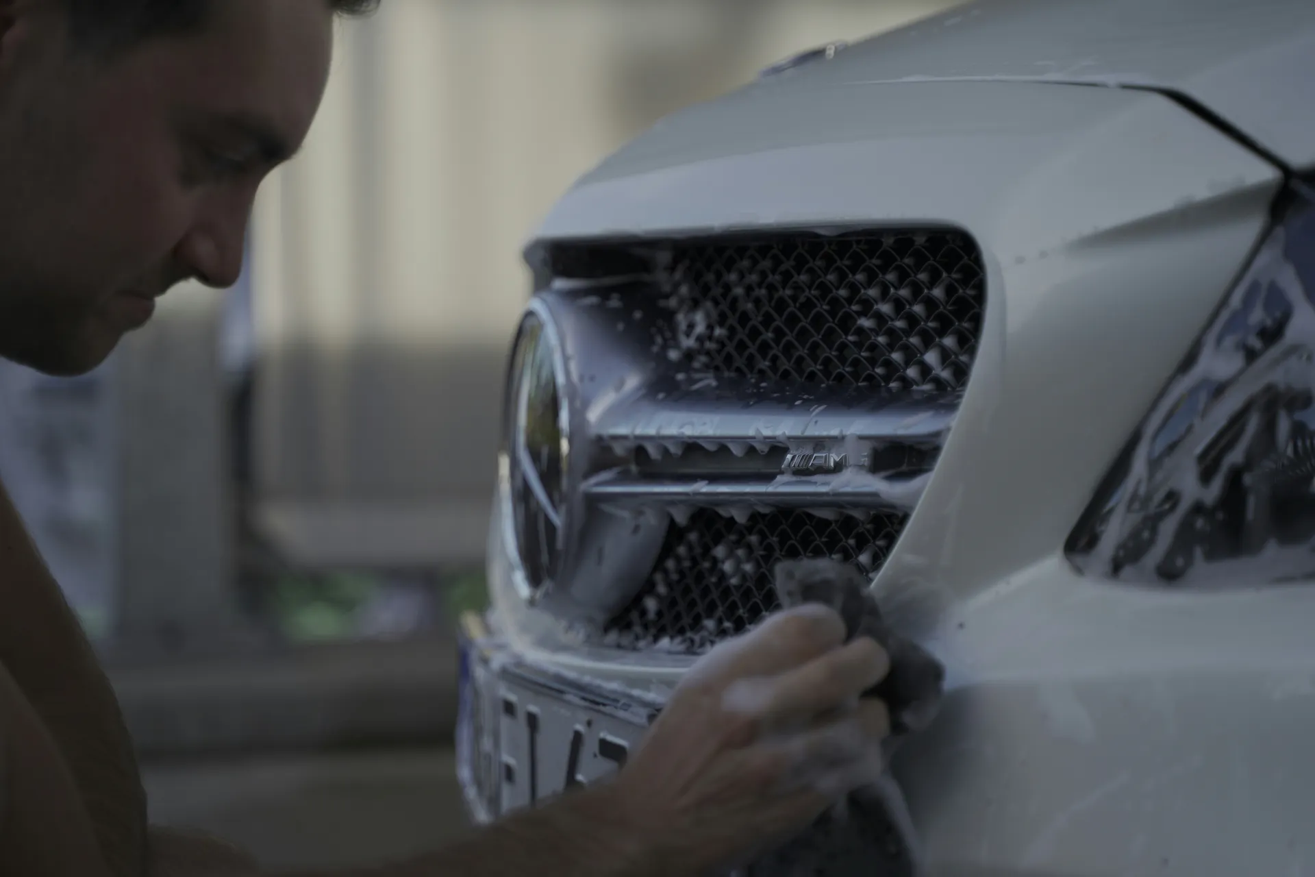 A close-up of someone washing and detailing the front of a vehicle.