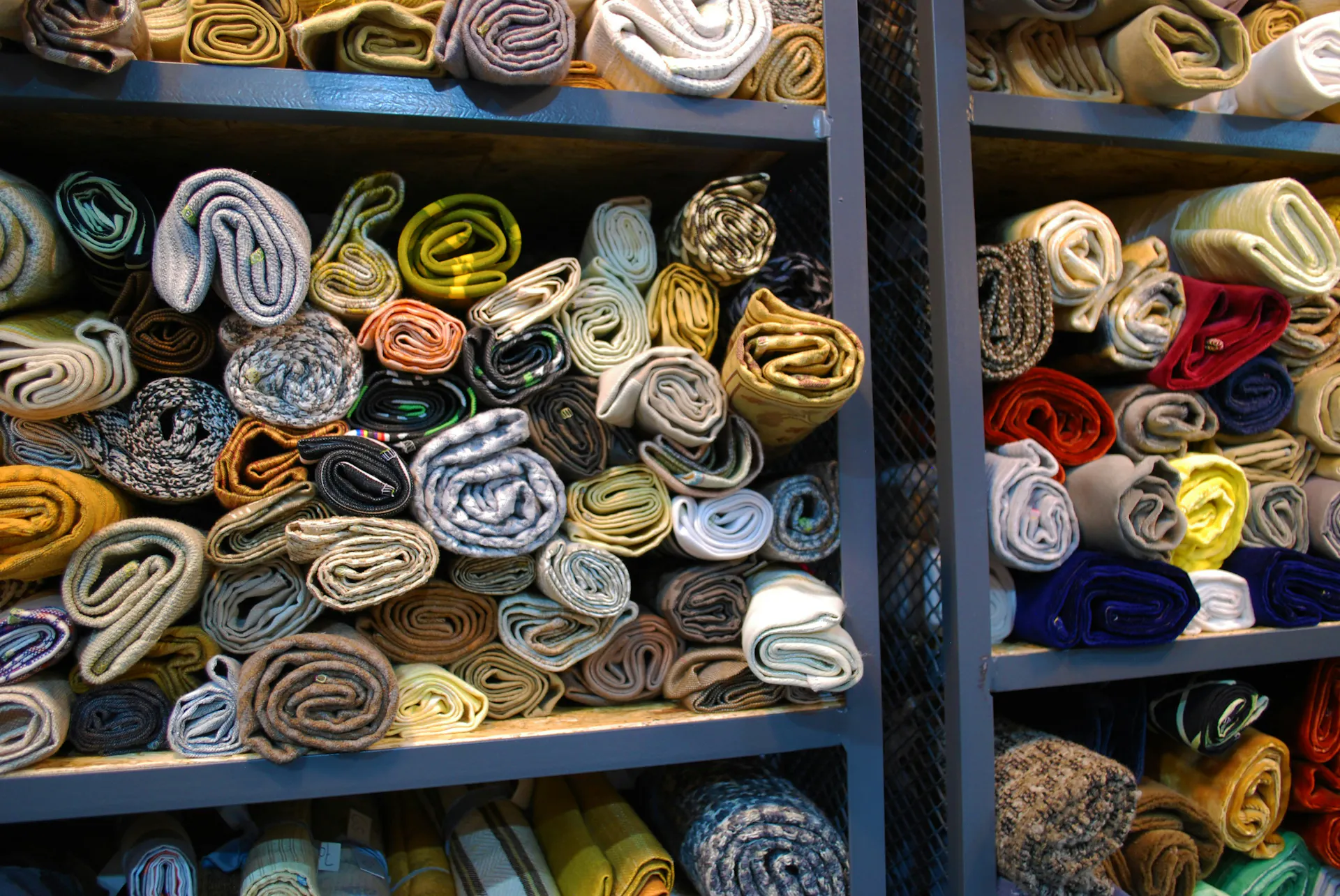 A storage shelf filled with various fabrics.