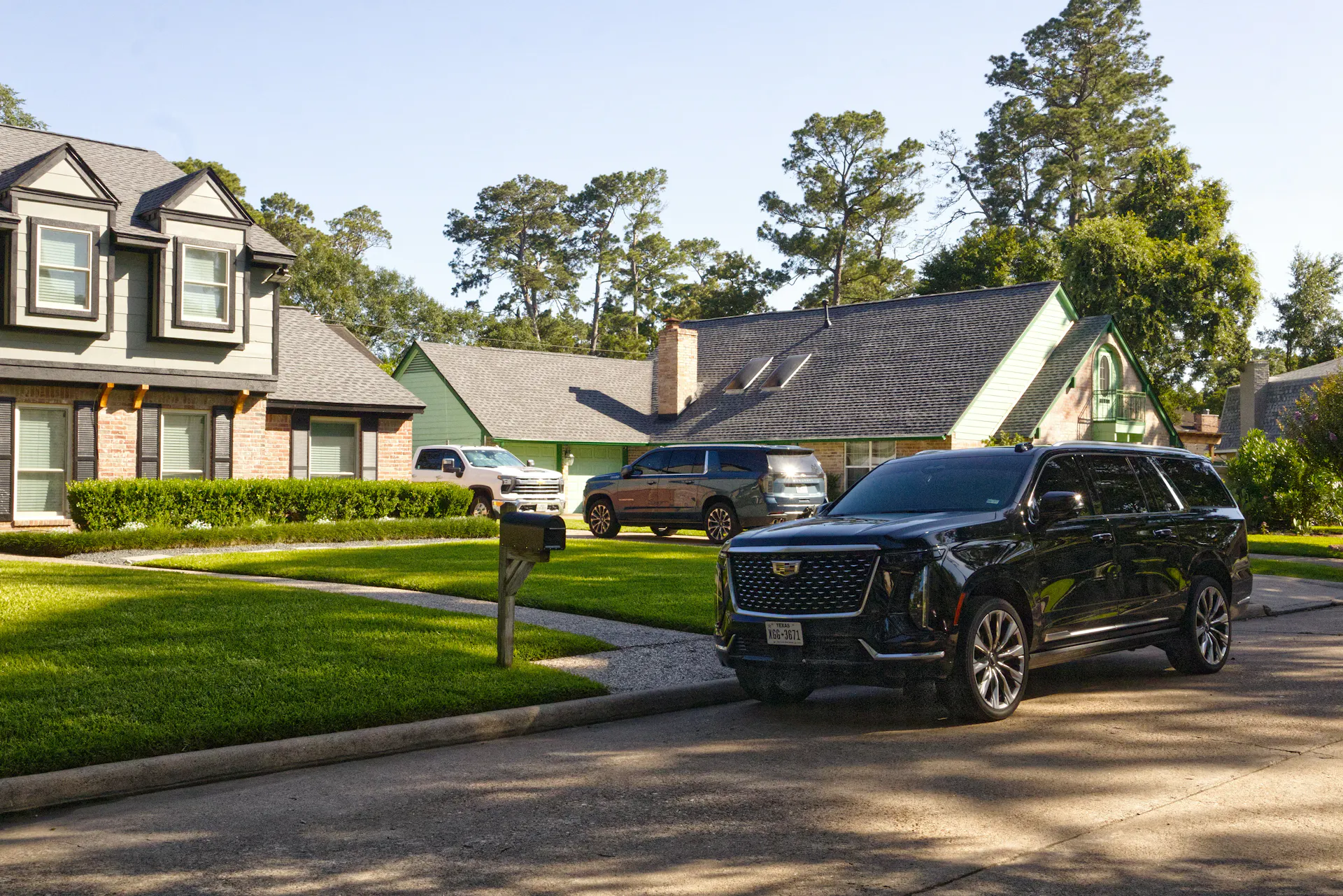 An SUV parked on a suburban street in front of a large house in Houston.