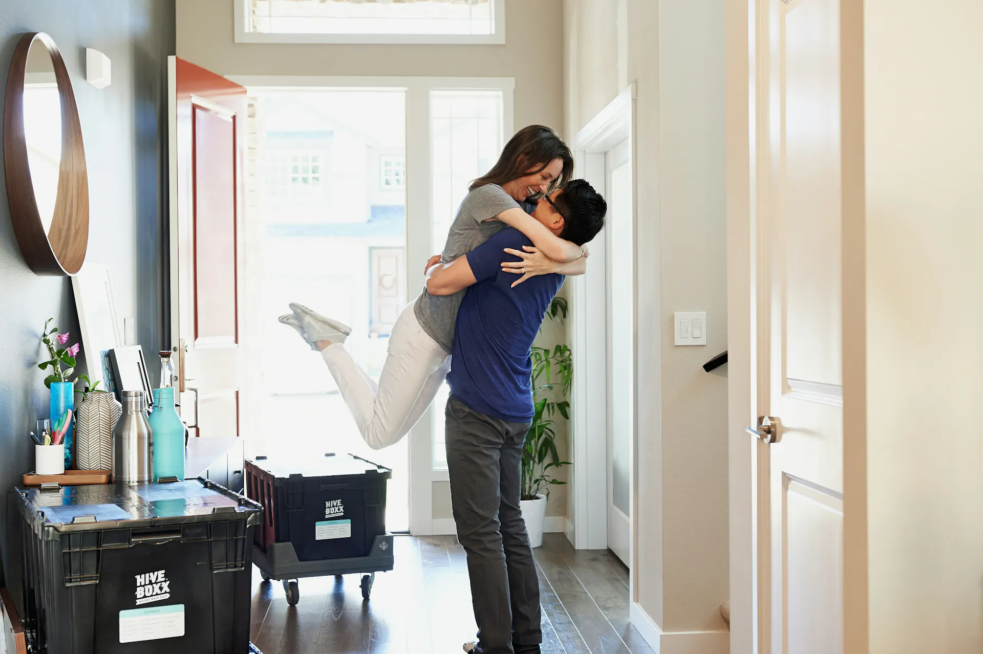 A happy couple, smiling and packing moving boxes for a cross-country move.