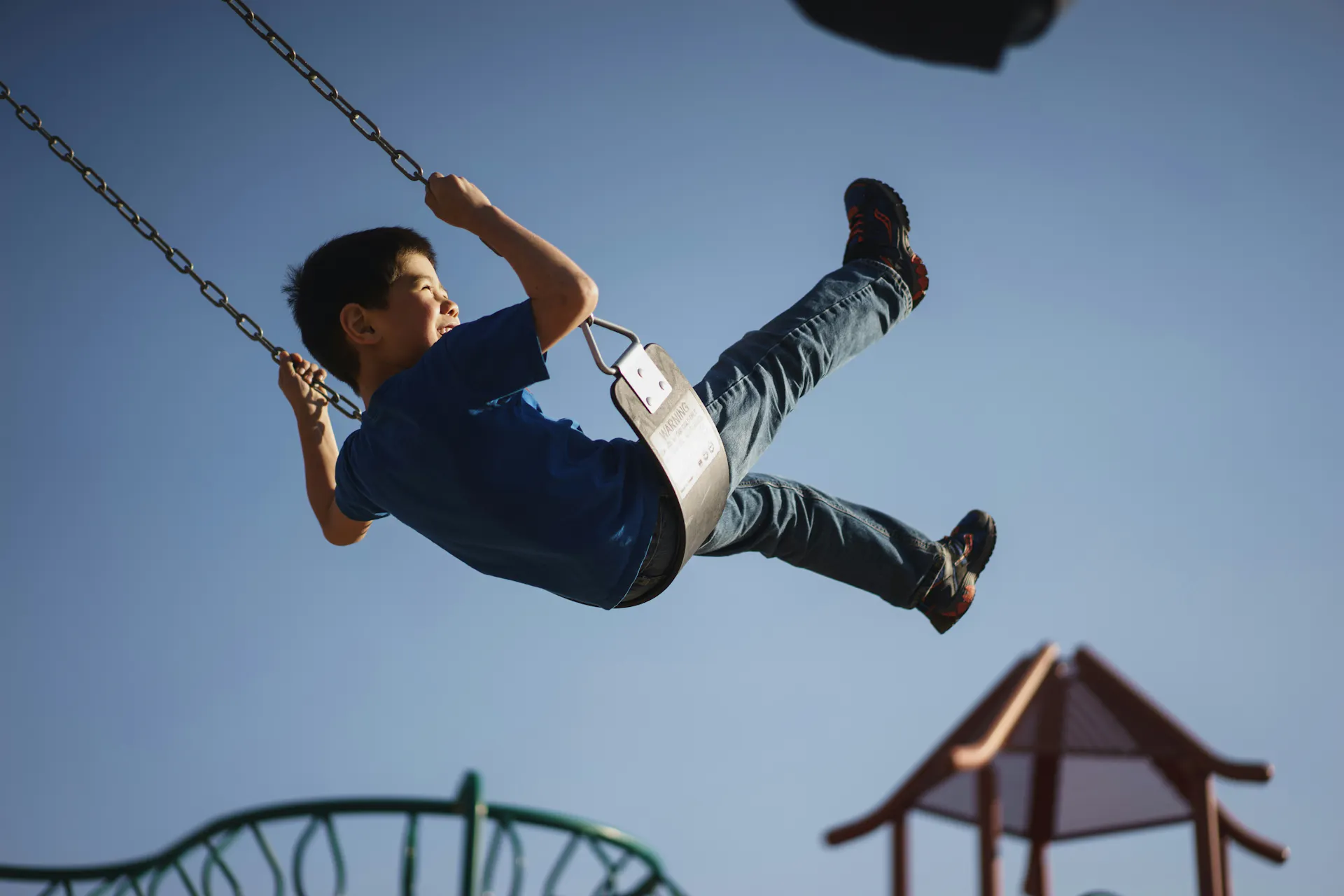 A child swinging high into the air on a playground swing at one of Madison’s many family parks.