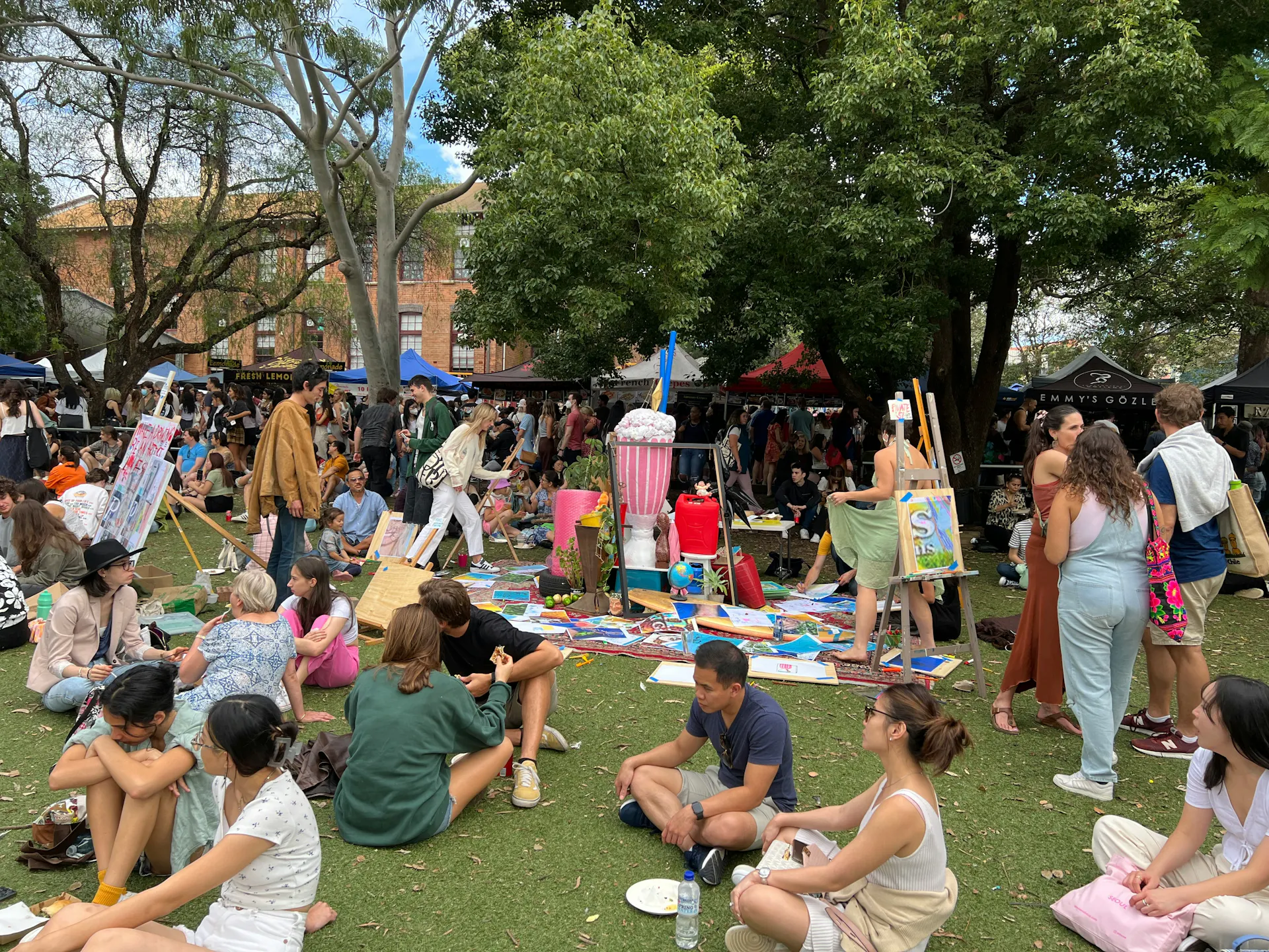 A group of people sitting in the grass next to an art festival over the summer in Auburn.