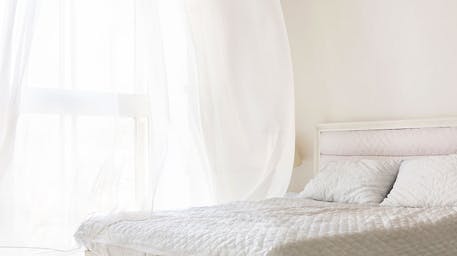 White bedroom with window open and air blowing through the window