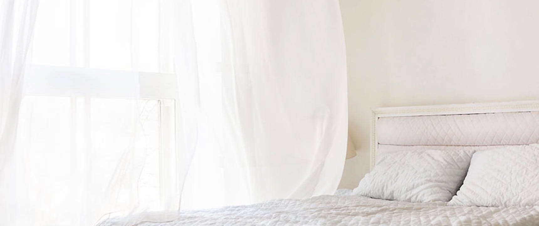 White bedroom with window open and air blowing through the window