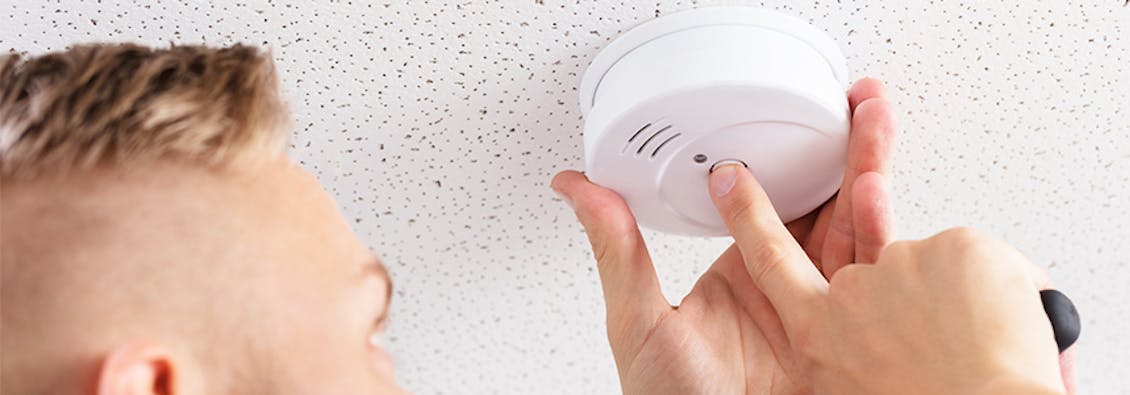 A person checking a smoke detector