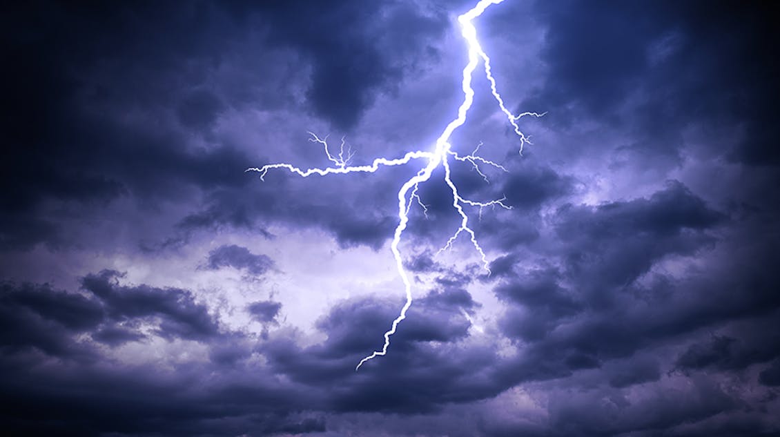 Purple sky with black clouds and a bolt of lightning