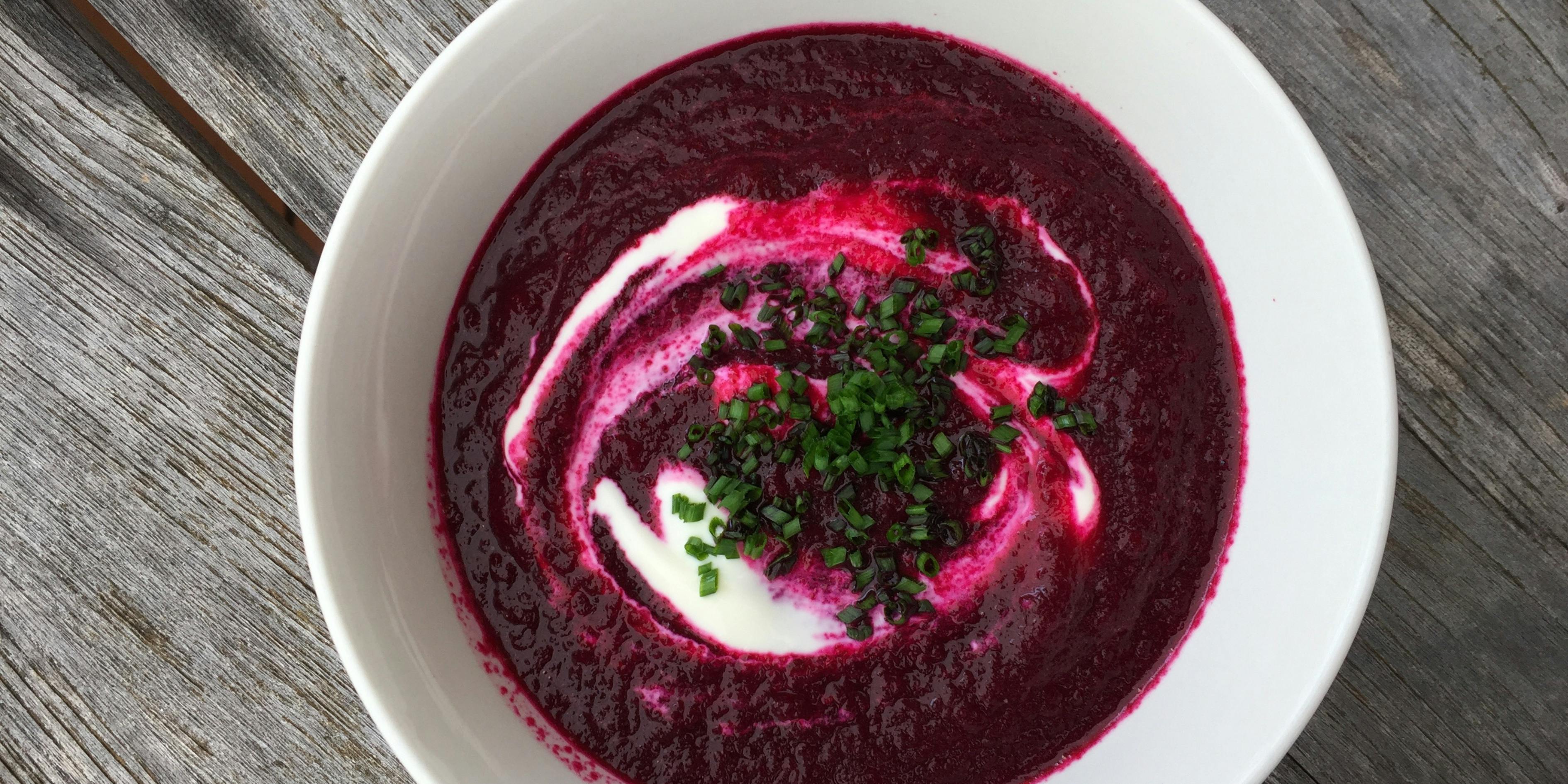 A bowl of beetroot soup with a swirl of creme fraiche and chopped chives 
