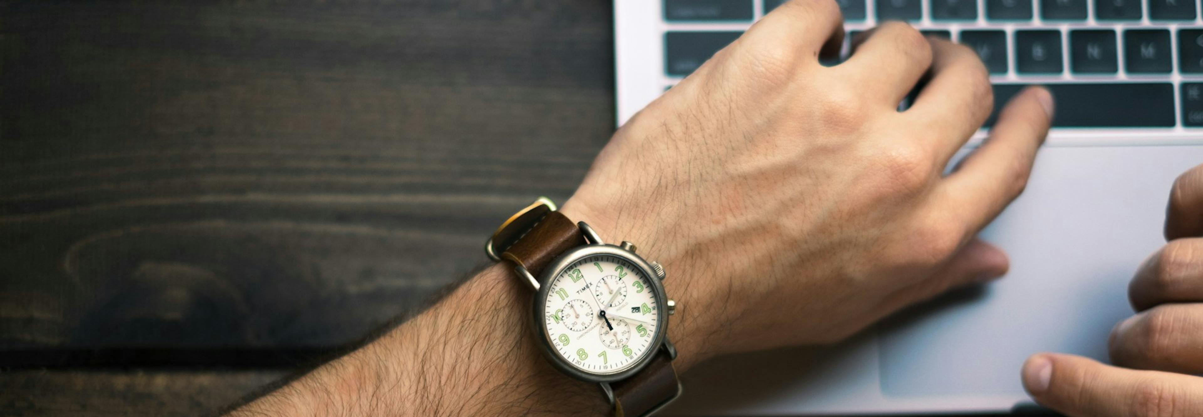 Coder looking at their watch over a computer keyboard