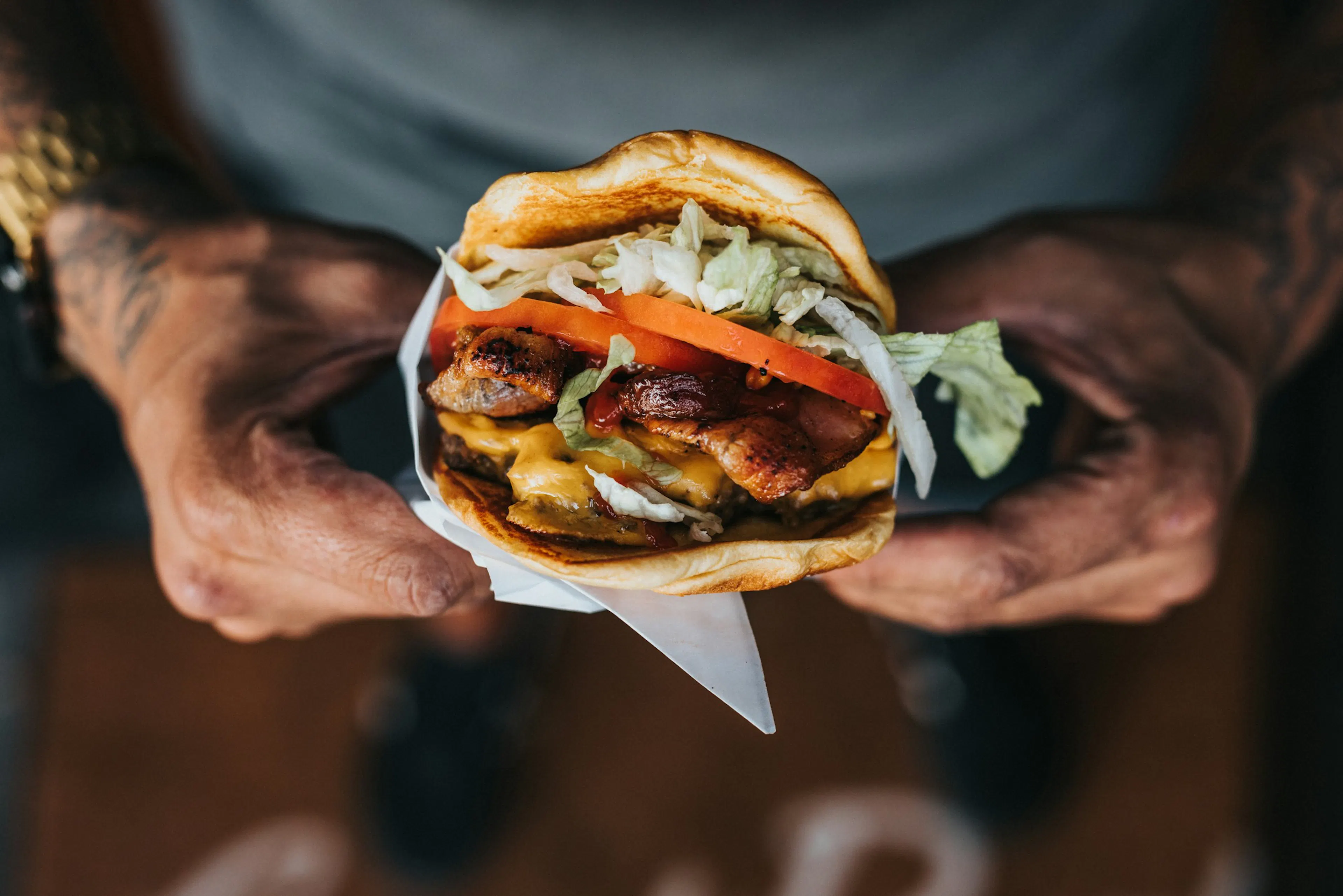 Hamburgare med bacon, ost och sallad som hålls fram