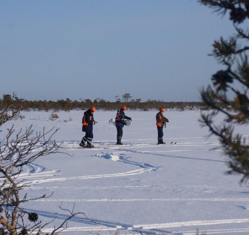 Three people deploying STRYDE nodes for a seismic survey in the snow