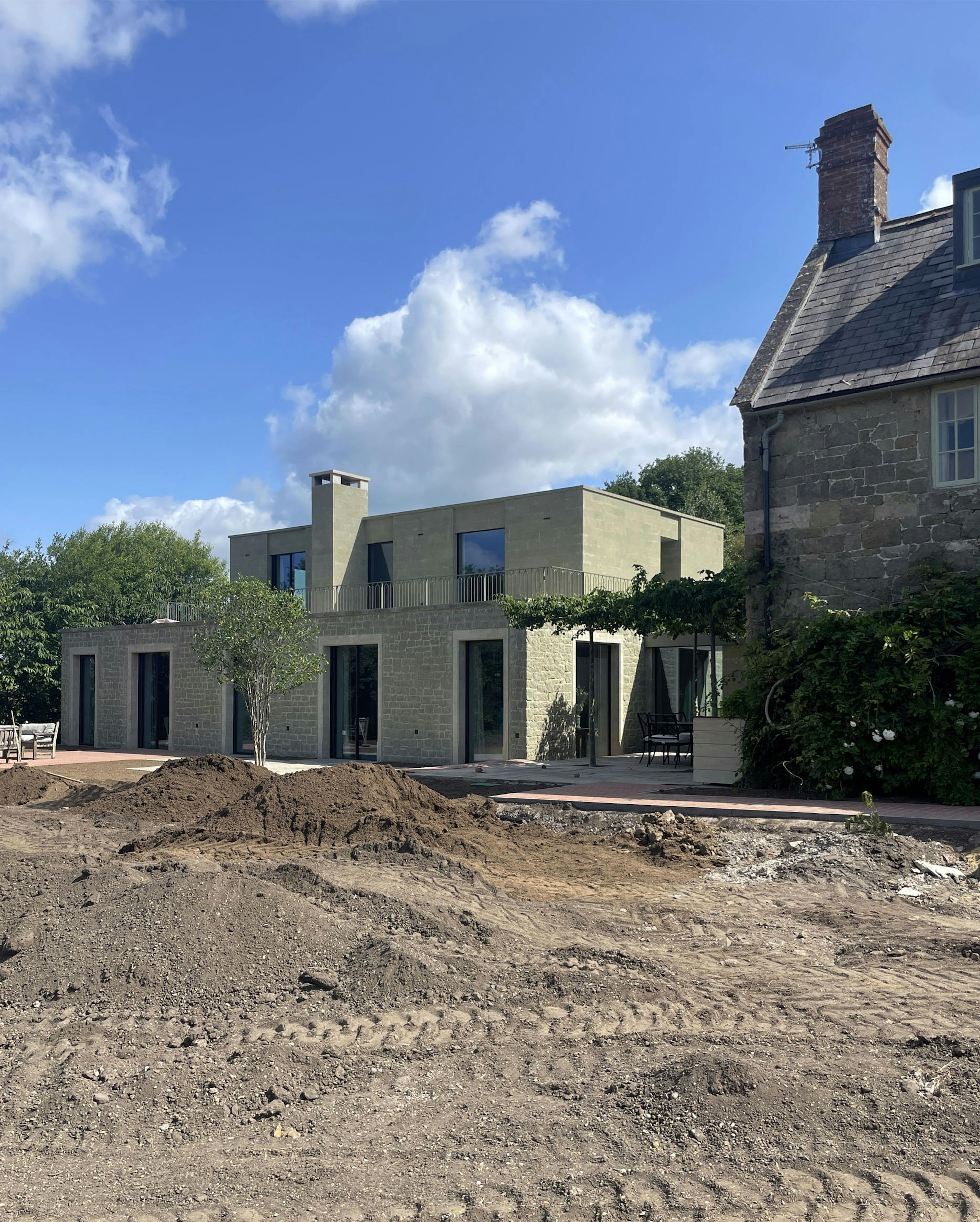 A modern green stone building under construction with a blue sky.