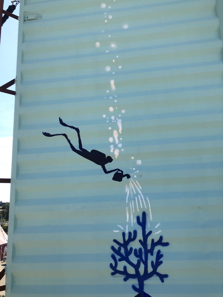 Illustration d'un plongeur arrosant un corail sur une structure de la zone libre d'art de Transfert.