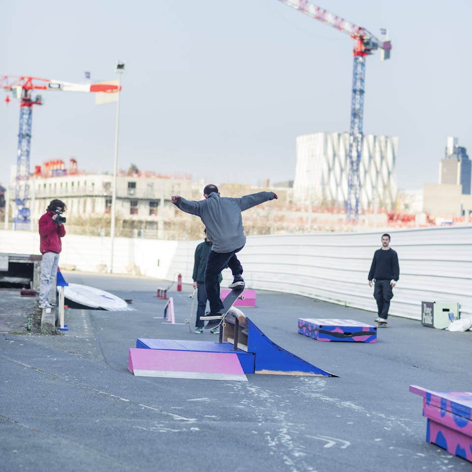 Skateur vu de dos s'élançant sur un module de skate en bois.