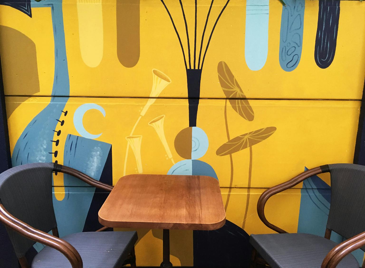 Une table de terrasse située juste devant l'oeuvre murale du Poum Poum T’Chak bar.