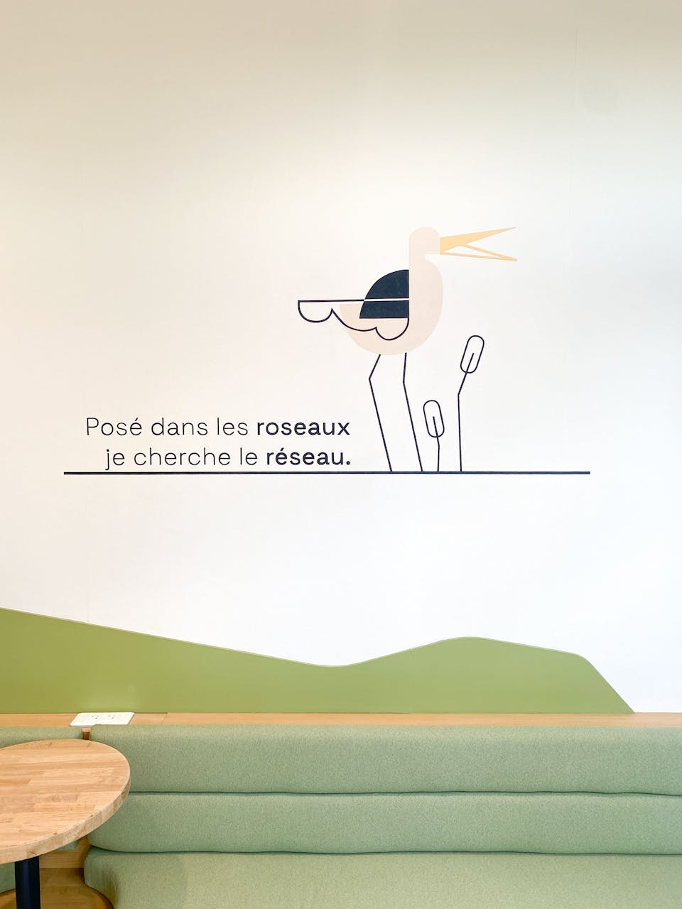 Une illustration filaire représentant un héron dans un marais, apposée par sticker dans le cadre de l'aménagement de la Maison de l'Entreprise à Saint-Nazaire par l'agence de design Studio Katra. On peut y lire "posé dans les roseaux, je cherche le réseau".