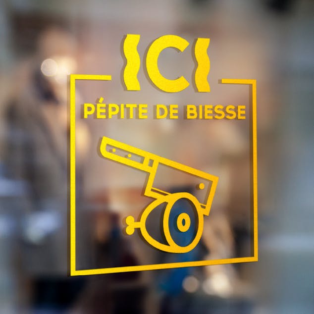 Sigle de certification et de recommandation issu de la nouvelle identité visuelle de la rue Biesse à Nantes, appliqué sur la vitrine d'une boucherie.