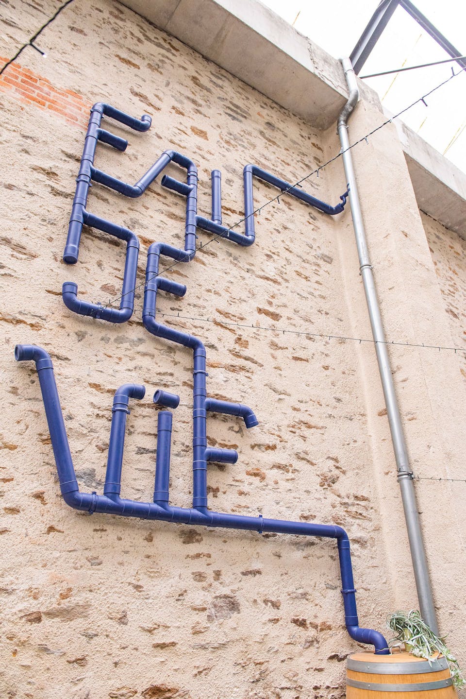 Un nudge urbain au cœur des locaux de l'entreprise Valeuriad, utilisant une gouttière en tant que récupérateur d'eau de pluie. La gouttière forme en elle même les mots "eau de vie".