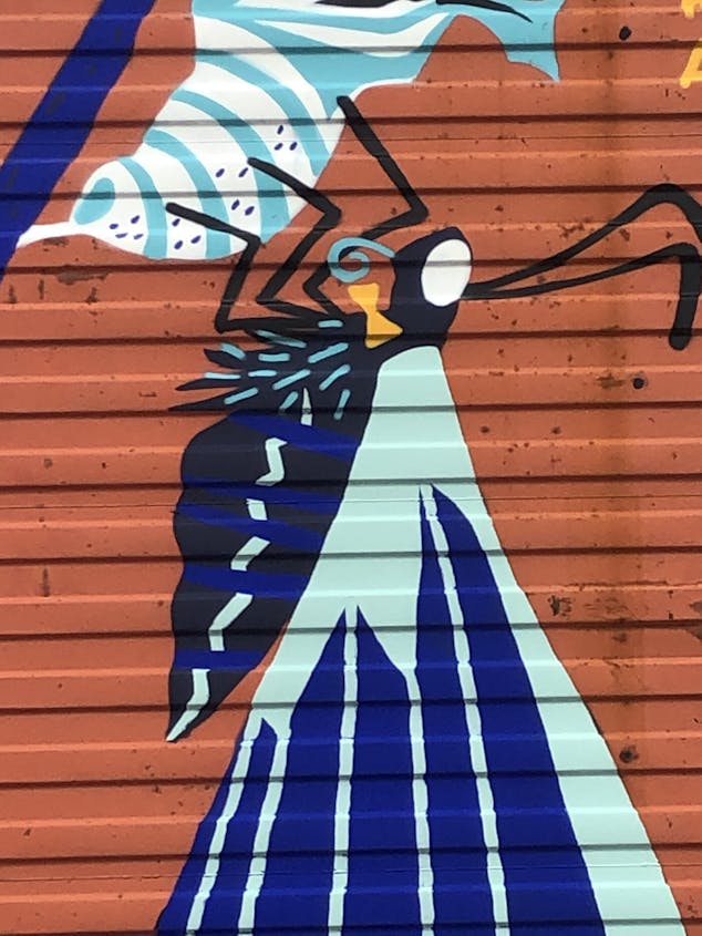 Fresque murale extérieure d'un papillon sortant de sa chrysalide, réalisée sur un conteneur.