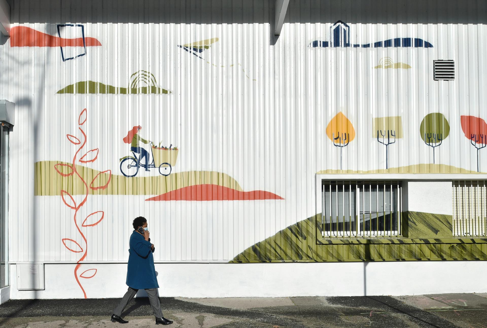 Une jeune femme déambule devant la peinture murale du Studio Katra faite à Labo Diva.