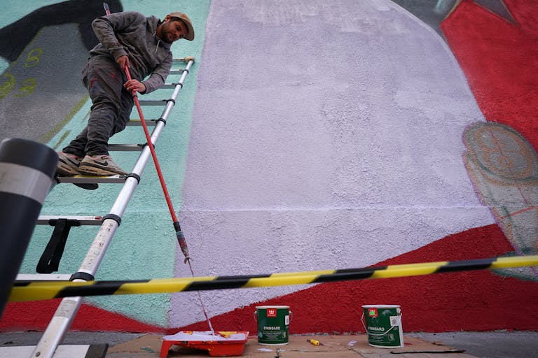 Antoine, CEO du Studio Katra, utilise une échelle télescopique pour peindre la fresque de Cluj-Napoca.