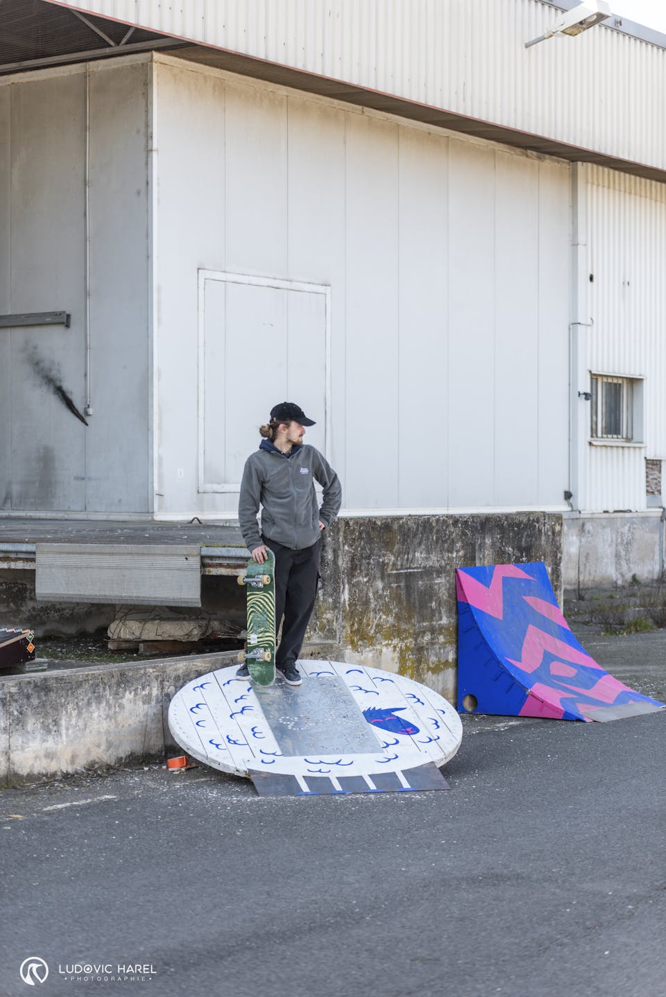 Skateur debout sur un module, planche à la main.