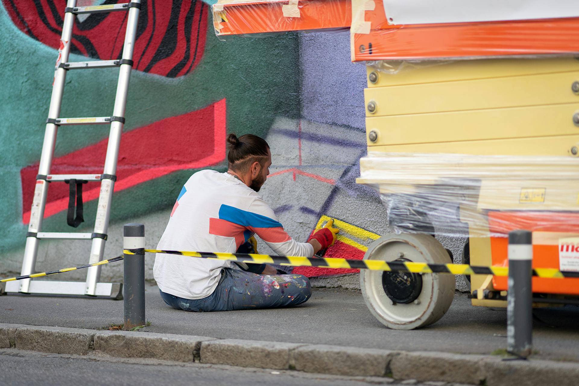 Camille, designer du Studio Katra s'assoit par terre pour travailler en détails le bas de la fresque.