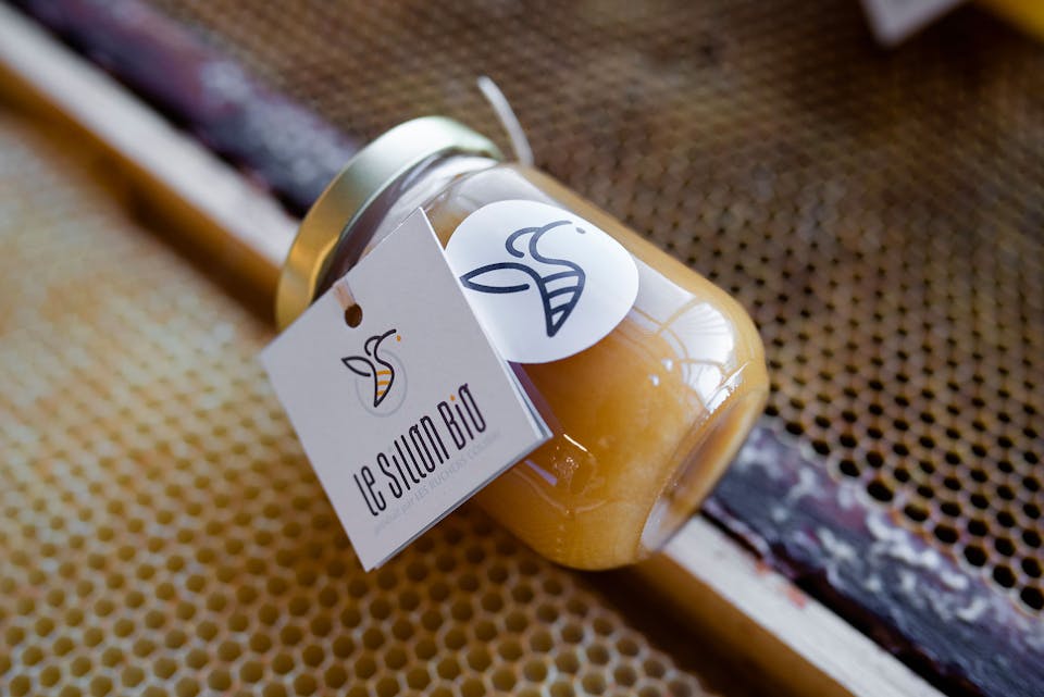 Un pot de miel étiqueté selon l'identité visuelle du Sillon Bio.