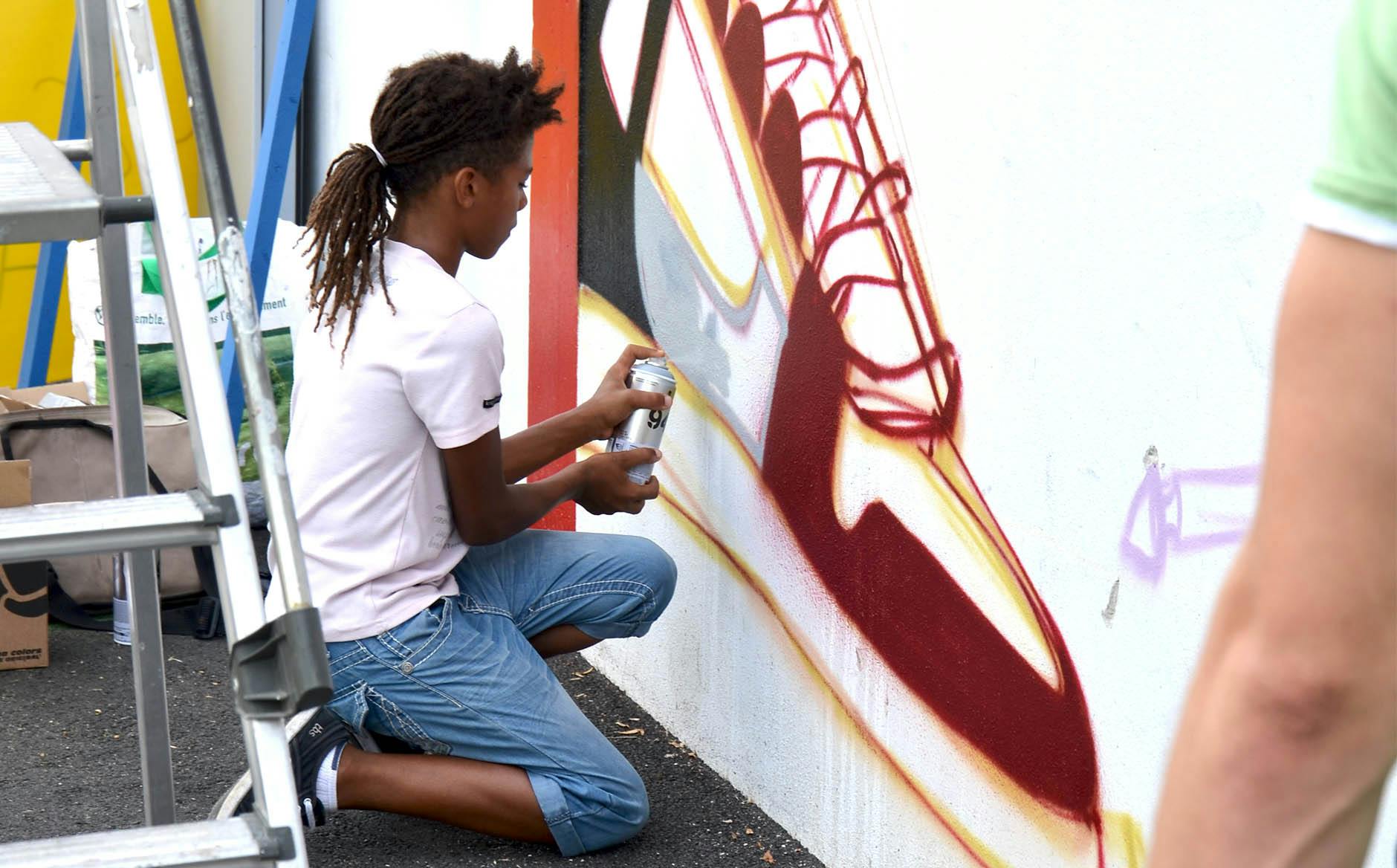 Un jeune garçon s'essaye au graffiti lors de l'édition 2016 d'Urban Culture en compagnie du Studio Katra.