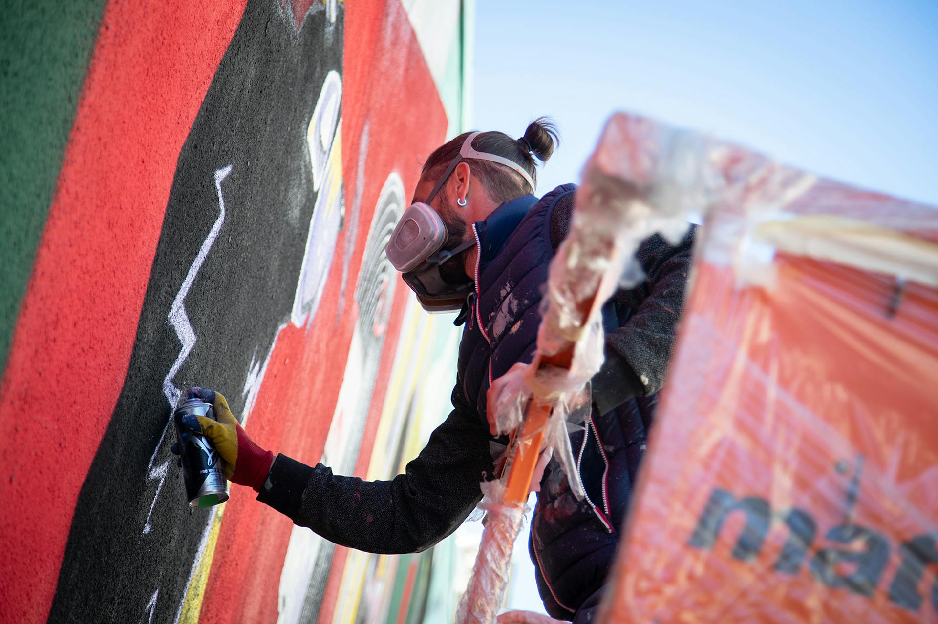 Camille, un designer du studio de design graphique Katra, peignant à la bombe un mur en Roumanie.