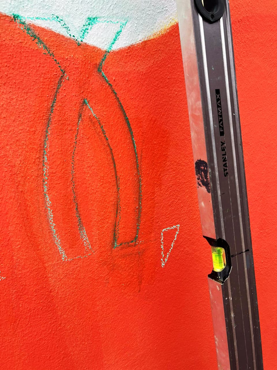 Niveau à bulles apposé contre un mur sur un chantier fresque du Studio Katra.
