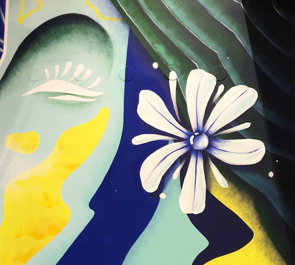 Détails d'une fresque murale intérieure. Le plan met en évidence une fleur accrochée aux cheveux d'une femme.