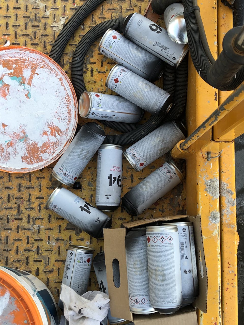 Des bombes de peinture posées en vrac sur le sol.