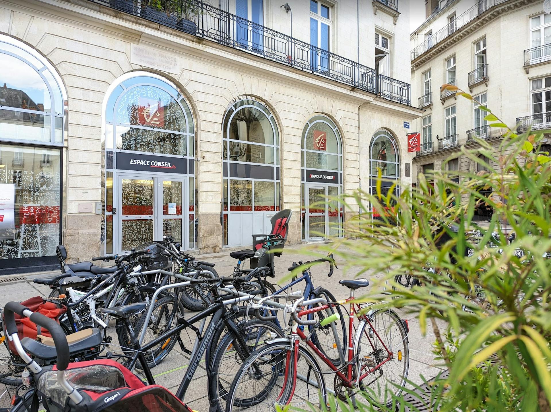 Des vélos garés devant l'entrée de la Caisse d'Épargne sur la place Graslin à Nantes.