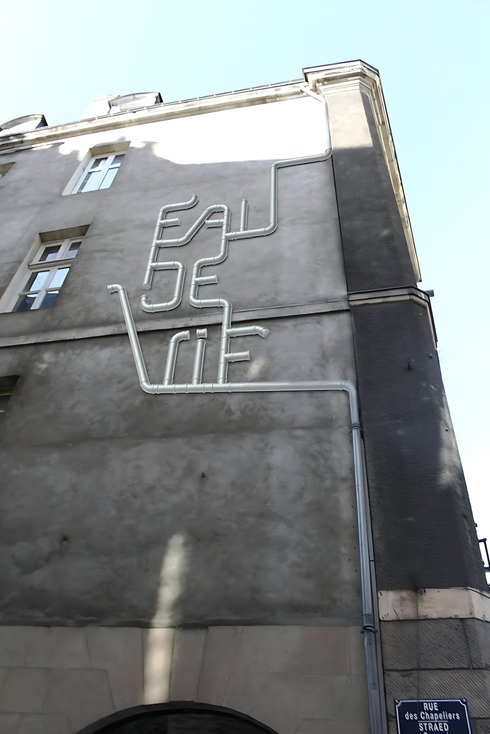 Mise en perspective d'un récupérateur d'eau sur la façade d'un bâtiment.