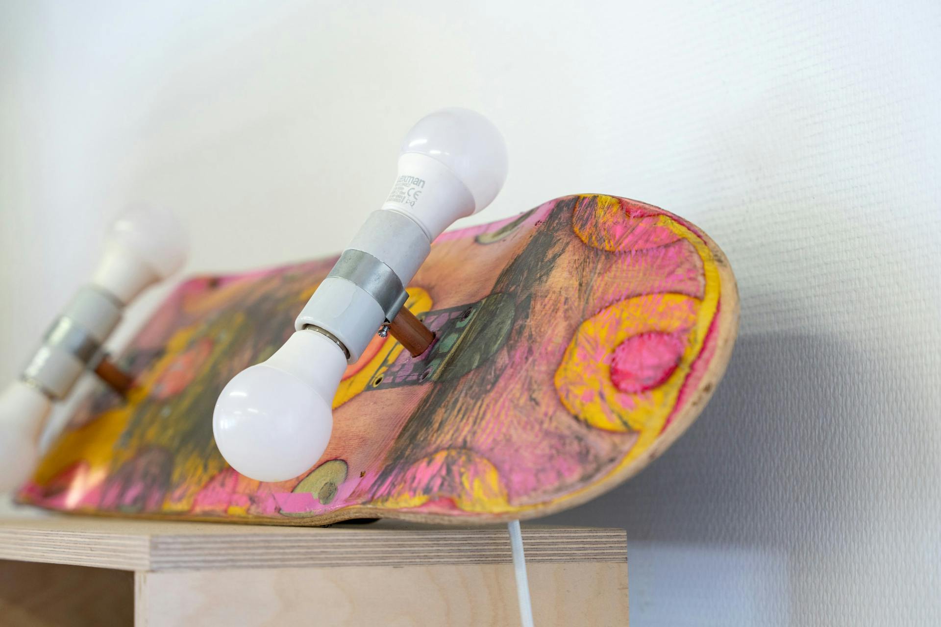 Une lampe-skateboard sur une étagère, dont les roues sont des ampoules.