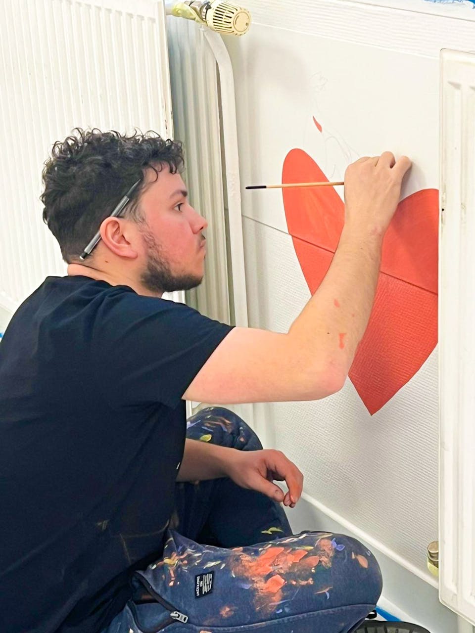 Felix, designer graphique chez Studio Katra, peint une partie de la signalétique dédiée à la nouvelle salle d'attente des urgences pédiatriques du CHU de Montpellier.