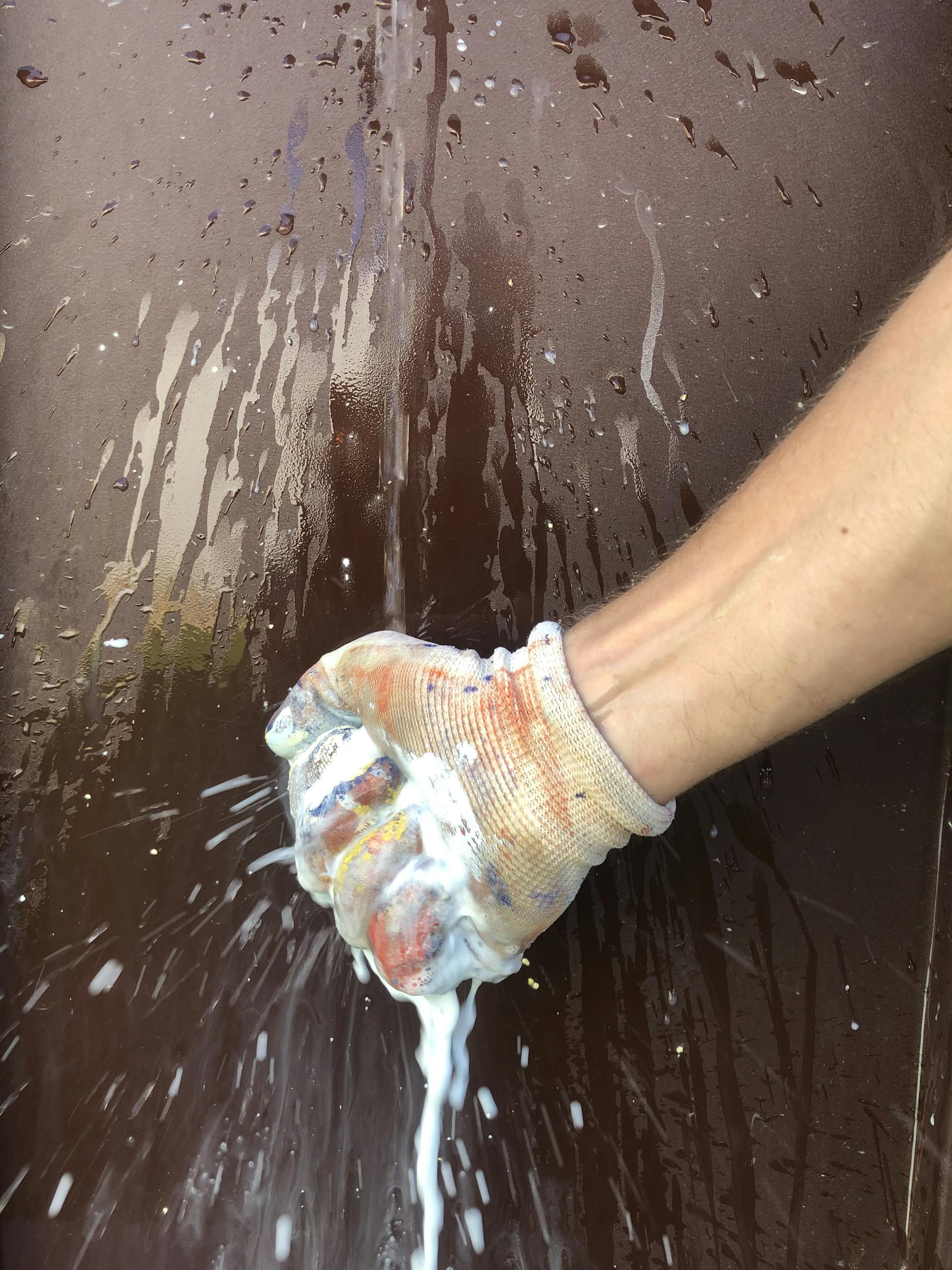 Une main compresse une éponge pour en extirper la peinture qu'elle vient d'appliquer.